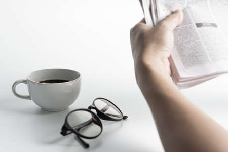 White coffee cup,glasses,and a man read News paper on the white tableの写真素材