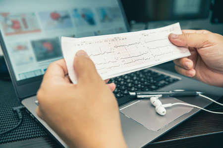 Close up Heart rate result graph paper document electrocardiogram  in hand a man analysis of medical...