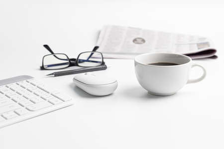 Coffee cup keyboard mouse of computer desktop in business concept and newspaper glasses and pencil in backgroundの写真素材