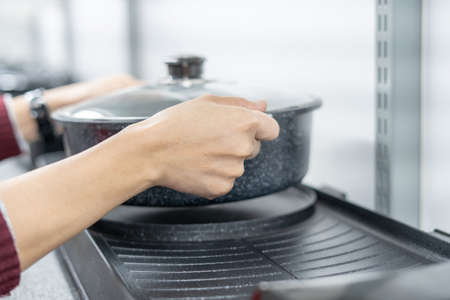 Hand women check electric pan on the shelves of the market mall