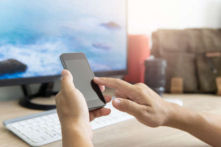 Man use smartphone and computer search for attractions and map for trip and camera lens bag and wireless speaker in backgroundの写真素材