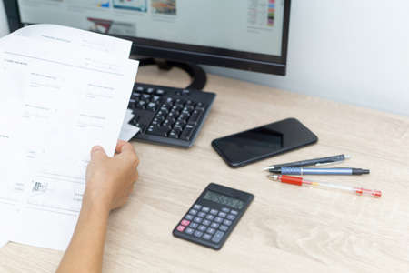 Close up hand teacher looking example sheet and examination  equipment on the wood table in the backgroundの写真素材