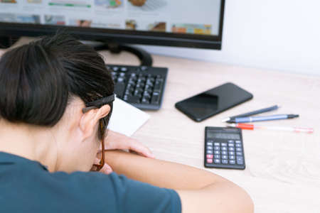 Blur concept of Teacher woman tired Lie down on the wood table and piles of papers and examination ...