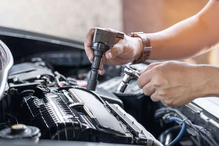 Close up spark plug coil in hand a man and use block wrench remove a bolt in service in garage and engine room  backgroundの写真素材