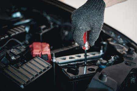 Close up hand a man wear glove use screwdriver open a cap battery for add distilled : maintenance and inspections for extended service life battery of carの写真素材
