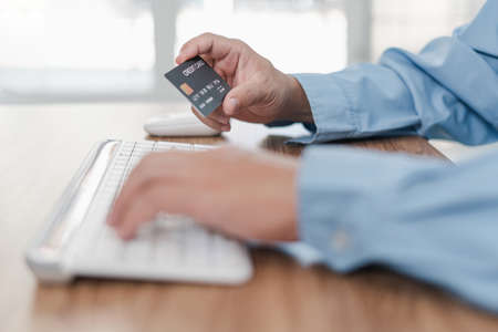 Hand a man hold credit card and typing on computer desktop keyboard working and pay money in...