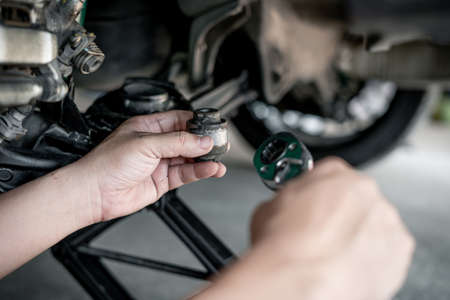 Close up hand a man hold old Rubber bush joint component and wrench part of car suspension in service shop and maintenance in service workの写真素材