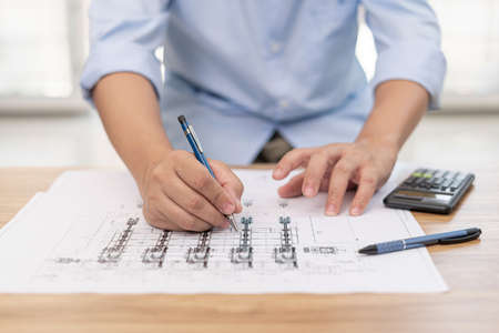 Engineering work concept : Close up hand a use pencil mark CAD drawing and calculator in Calculating...