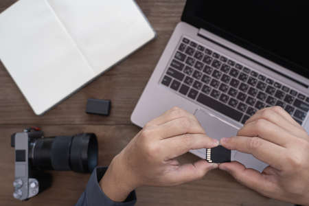 Close up memory card of camera in hand a man and camera and photography equipment on tableの写真素材