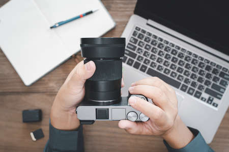 Close up camera in hand a business man work photo with memory,battery,notebook,pen,laptop computer...