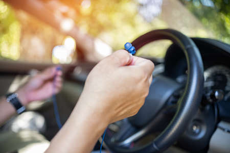 Close up ear phone in hand a man connect to smartphone use for  hand free with drive a car : safety...