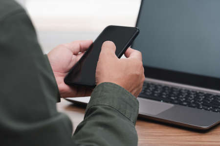 Business man holding smartphone and touch and typing on screen for online working and use desktop...