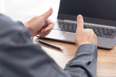 Business man thumbs up for work on the project successfully using computer and writing on a paper on...