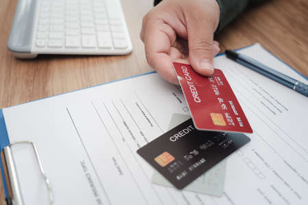 Close up hand a man hold credit cards on insurance document for payment of Annual car insurance...