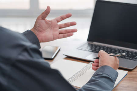 Action working concept : Business man use laptop computer and a pen write memo on note book paper...