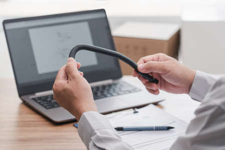 Hand a man hold oil hose rubber of car, service part and use laptop check spec in stock for accuracy...
