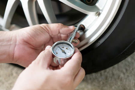 Car basic check : close up A man hold air pressure gauge check tire air pressure of wheel in service conceptの素材 [FY310182217343]