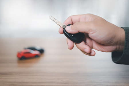 Close up hand of man holding and push remote control for lock and Un-lock car : concept model toy a...