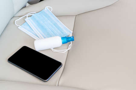 Alcohol spray mask and smartphone are placed on the car seat basic antivirus protection equipment In car use everydayの写真素材