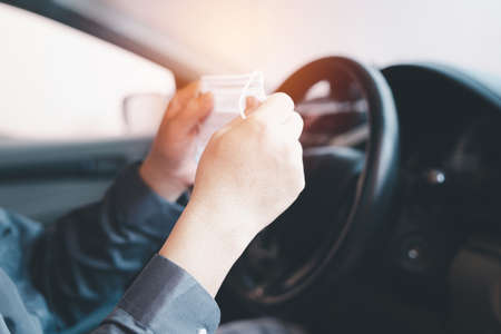 A man hold nose mask in hand and wear to prevent the virus from entering the body in a preliminary way in drive car every dayの写真素材