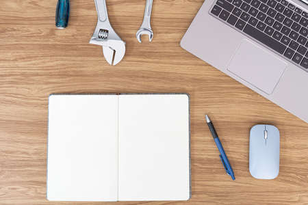 Top view photo of office equipment notebook pen  computer laptop and wrench on wood table service concept of car maintenanceの写真素材