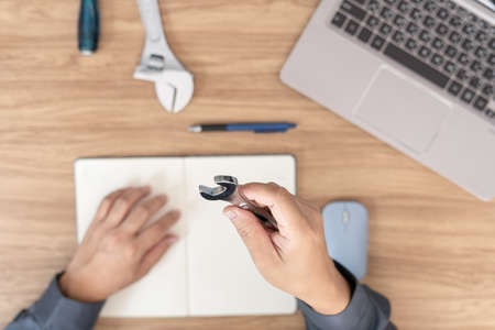 Top view photo : The technician hold a wrench in hand and used a computer laptop to analyze the broken of car in service room conceptの写真素材