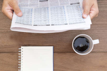 Coffee cup notebook paper on vintage wood table with a man read newspaper in coffee time