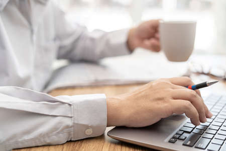 Man use computer laptop and drink coffee in morning time with work in office