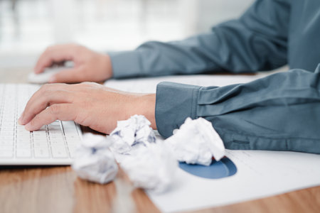 Hand a man typing on desktop keyboard and crumple paper on the wood table strain feeling was...