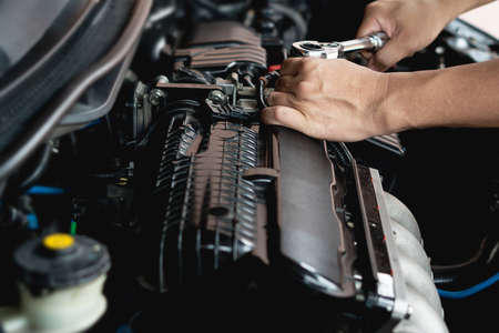 Closeup spanner in hand male mechanic repairs car in garage. Car maintenance and auto service garage...