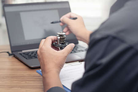Hand a man hold car thermostat of engine use laptop computer check new part in stock compare and...