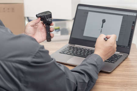 Hand a man hold old coil spark plug engine gasoline and use laptop check spec of part to pick up from stock for replacement in car repairs : Business car service conceptの写真素材