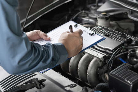 Close up hand car service staff check engine malfunctions and mistake check list in engine room : Car service conceptの写真素材