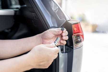 Close up hand a man hold screw nut of car tail lights with block wrench are being disassembled with the car body Maintenance of lighting systems for safety conceptの写真素材