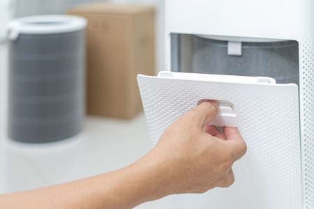 Hand a man open the lid of the air purifier check and change filter in side air purifier for dust...