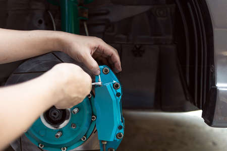 Man use open-end wrench adjust nut of nozzle brake caliper in brake fluid replacement for check and service brake system workの写真素材