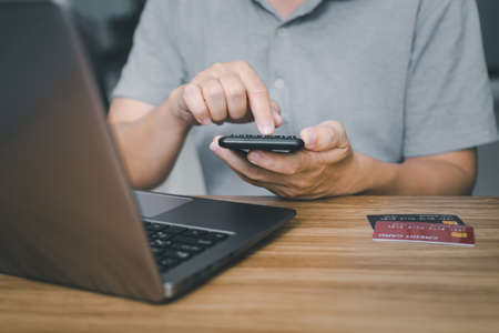 A man use calculator : calculate  Credit card expenses and laptop computer on wood table Financial planning conceptの写真素材