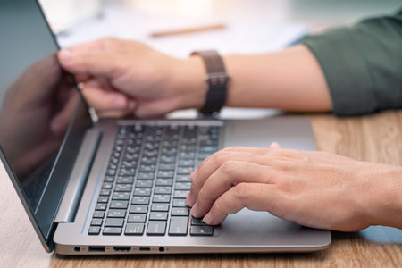Close up hand a man typing on laptop keyboard on wood deck and document in a blur background business conceptの写真素材