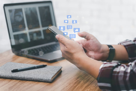 Social media concept. Man using smartphone connect to internet and laptop and notebook on tables working in homeの写真素材