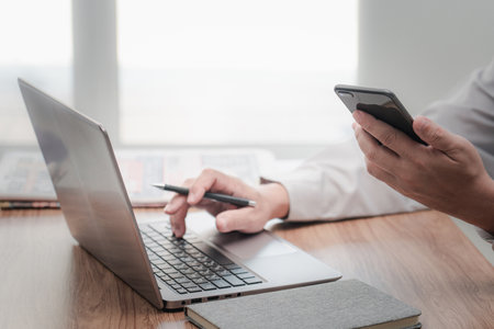 Businessman in the workplace. Texting message smartphone and use the laptop computer and office blur backgroundの写真素材