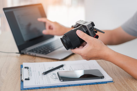 Car insurance officer holds the digital camera and check accident photo in monitor display, Check the terms of the warranty digital sheet in laptop, Car insurance concept in officeの写真素材