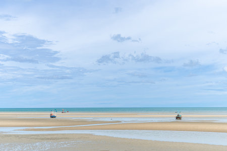 Fishing boats moored on a sandy beach at low tide. and the view of the sky near the rain beautiful natural scenery Khao Kalok Beach, Pranburi, Prachuap Khiri Khan Province  Landmarの写真素材