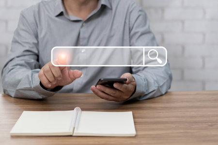Searching information data on internet networking concept. Man point on Searching screen and use smartphone connect to internet and notebook on the table with texture and copy spacの写真素材