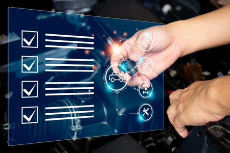 Car service business and smart virtual screen concept,Technician check car headlight bulb and basic item in smart checklist with car engine room in backgroundの写真素材