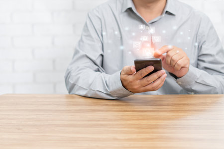 Social media concept. Man using smartphone connect to internet playing social media in home with white brick background for texture and copy spaceの写真素材