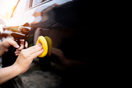 Car clean concept, Hand a man holding a sponge and clean spray wax to take care of the surface of the car from washingの写真素材