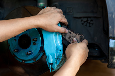 Car service and maintenance concept ,Serviceman holding brake pad and remove from brake caliper for check for conditions and abnormalities to repair brake system according to the period of useの写真素材