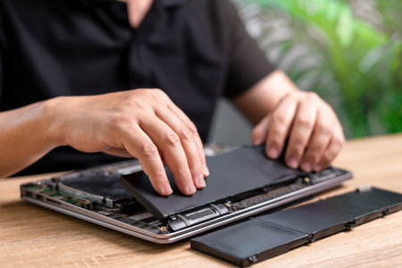 Laptop basic service of battery replacement, Technician Man holding the new battery and insert in the computer to repair laptop and remove the old part on the table to wait for removal, service workの写真素材