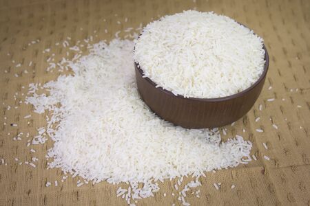 uncooked rice grains in wood bowlの写真素材
