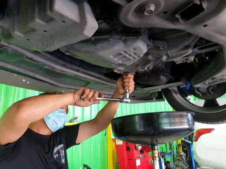 Bangkok, Thailand - July 17, 2021 : Unidentified car mechanic drain the old lubricant engine oil at car garage for changing the oil in a car engineのeditorial素材